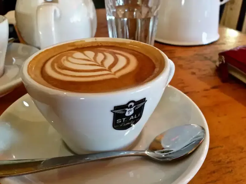 Barista menuang susu ke dalam cangkir kopi